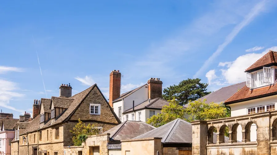 Tall brick chimney stacks with clay pots rising above pitched tile and slate roofs, the stacks where flashing leaks begin