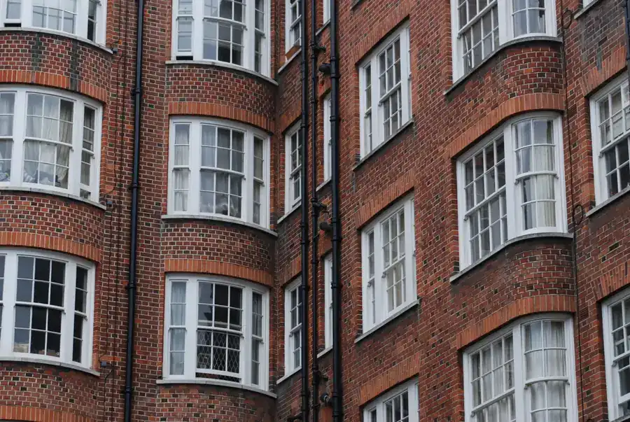 Black cast iron rainwater goods running down the brick elevation of a period mansion block