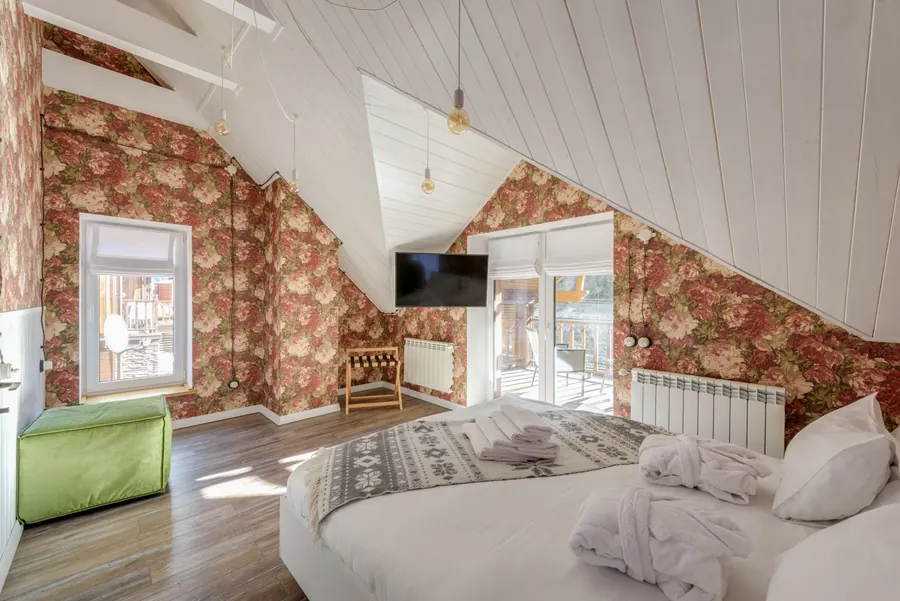 Bedroom built into a converted roof space with a sloping boarded ceiling and a window in the gable