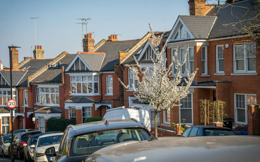 Red brick Edwardian houses with gabled bays and tiled roofs along a south London street