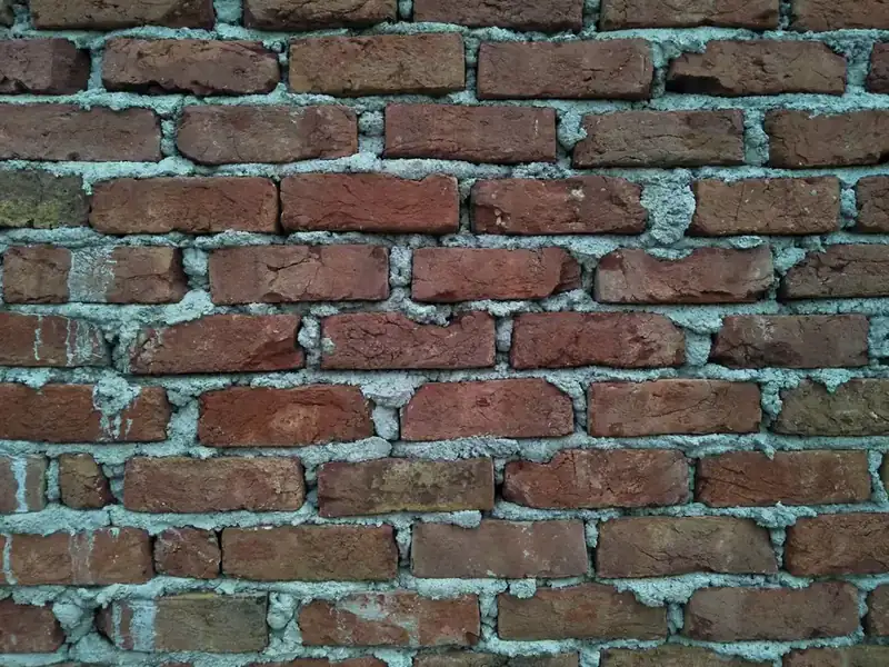 Close view of weathered brickwork with eroded and cracked mortar joints, the same kind of failure that opens up cement fillets at roof abutments in Croydon