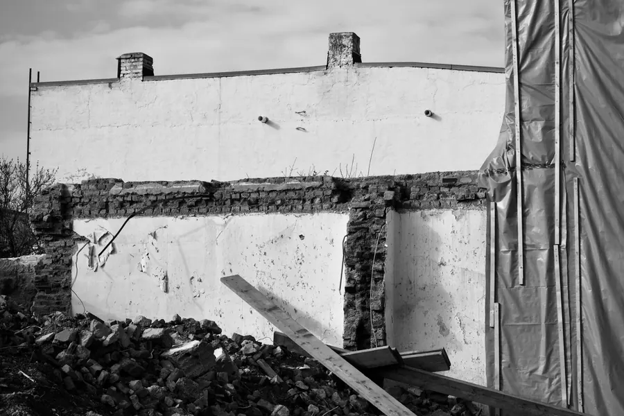 Exposed party wall left standing after a house was demolished, showing the outline of the old roof slope and a chimney stack on the wall line