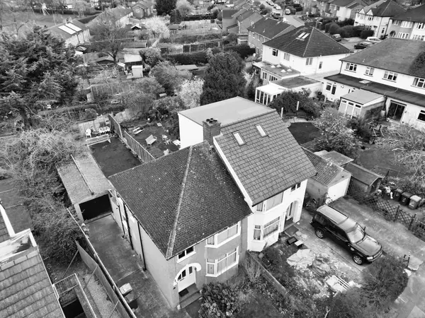 Aerial view of a hipped roof 1930s semi-detached house beside its neighbour, which has been re-roofed in concrete tiles with rooflights