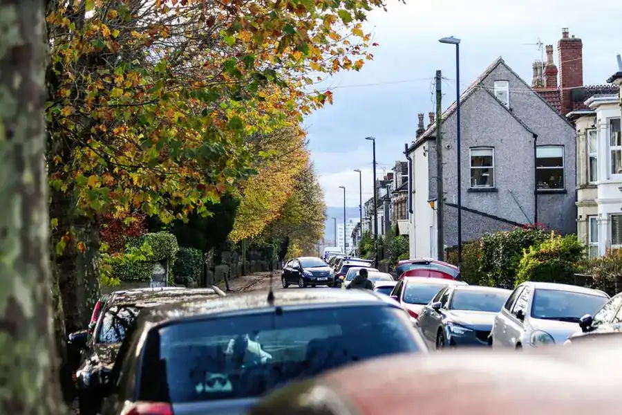 Cars parked nose to tail along a residential terraced street