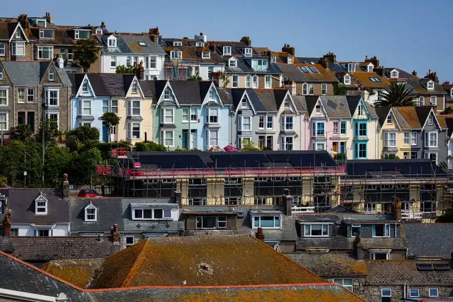 Scaffolding erected against terraced houses on a narrow residential street