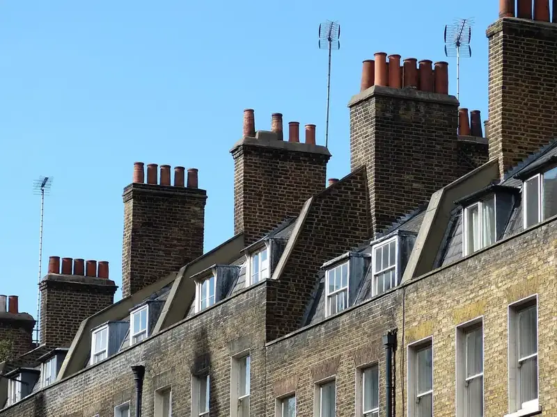 Terrace of London stock brick houses with shared chimney stacks, clay pots and slate dormers