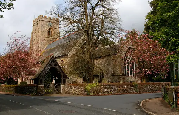 Old stone parish church with a lychgate and spring blossom in the churchyard
