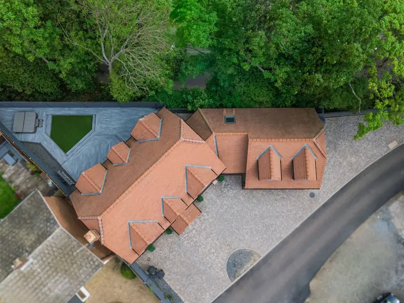 Overhead view of a large detached house with a complicated tiled roof of hips, valleys and dormers