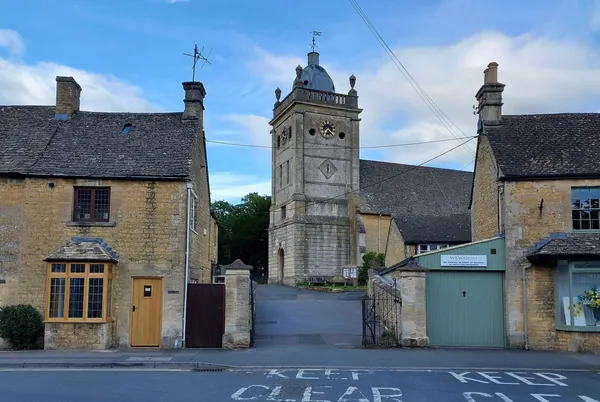 Stone clock tower at a road junction between older buildings
