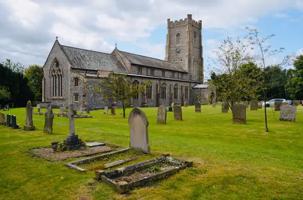 Medieval flint church with a square tower and gravestones in the churchyard