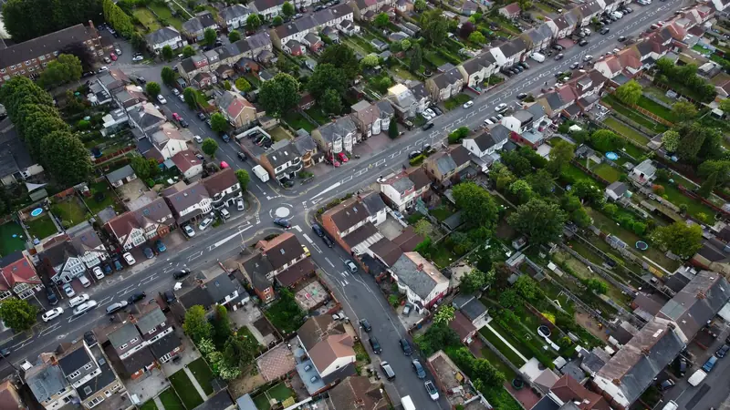 Aerial view of interwar suburban streets with rows of tiled roofs and long back gardens